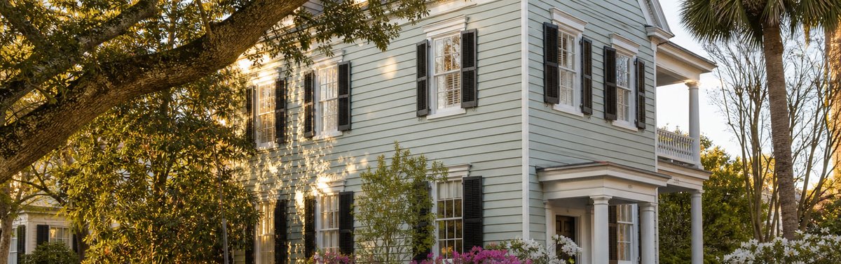 Charleston-style home with porch and flowering shrubs