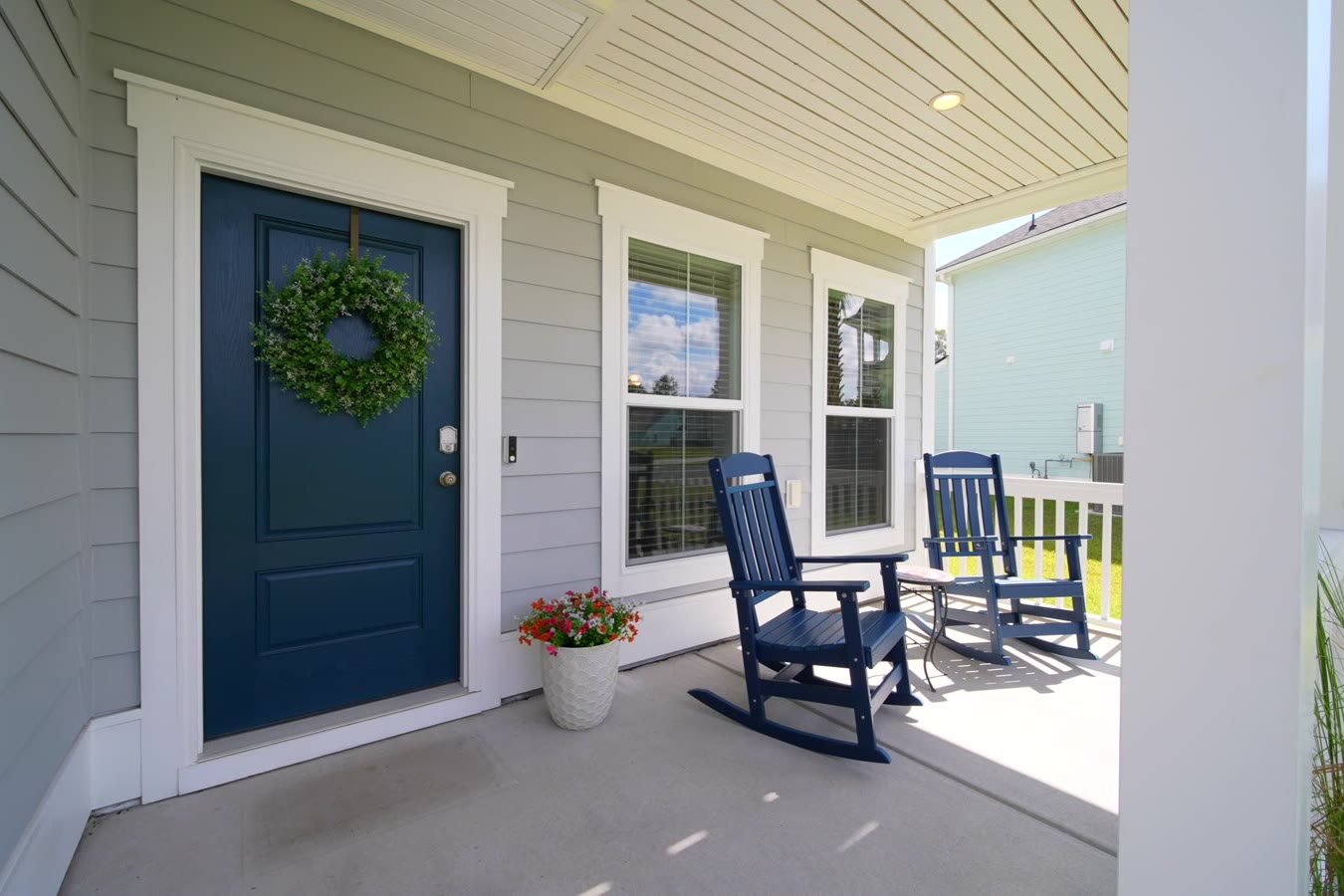 Navy front door with a boxwood wreath on the front porch